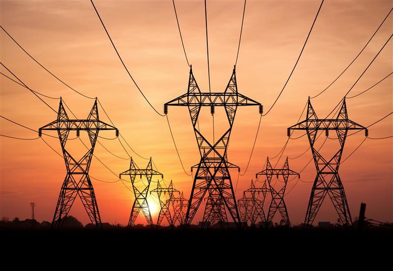 Multiple powerline towers with a sunset in the background