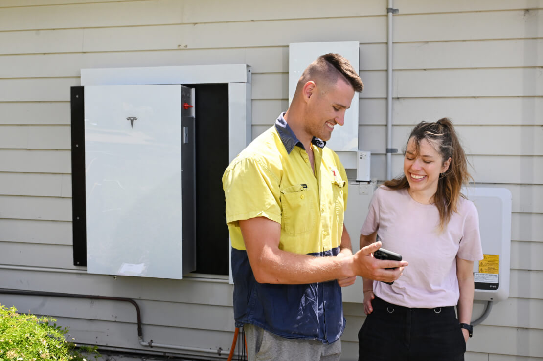 A man and a woman looking at a smartphone outside a residential household.