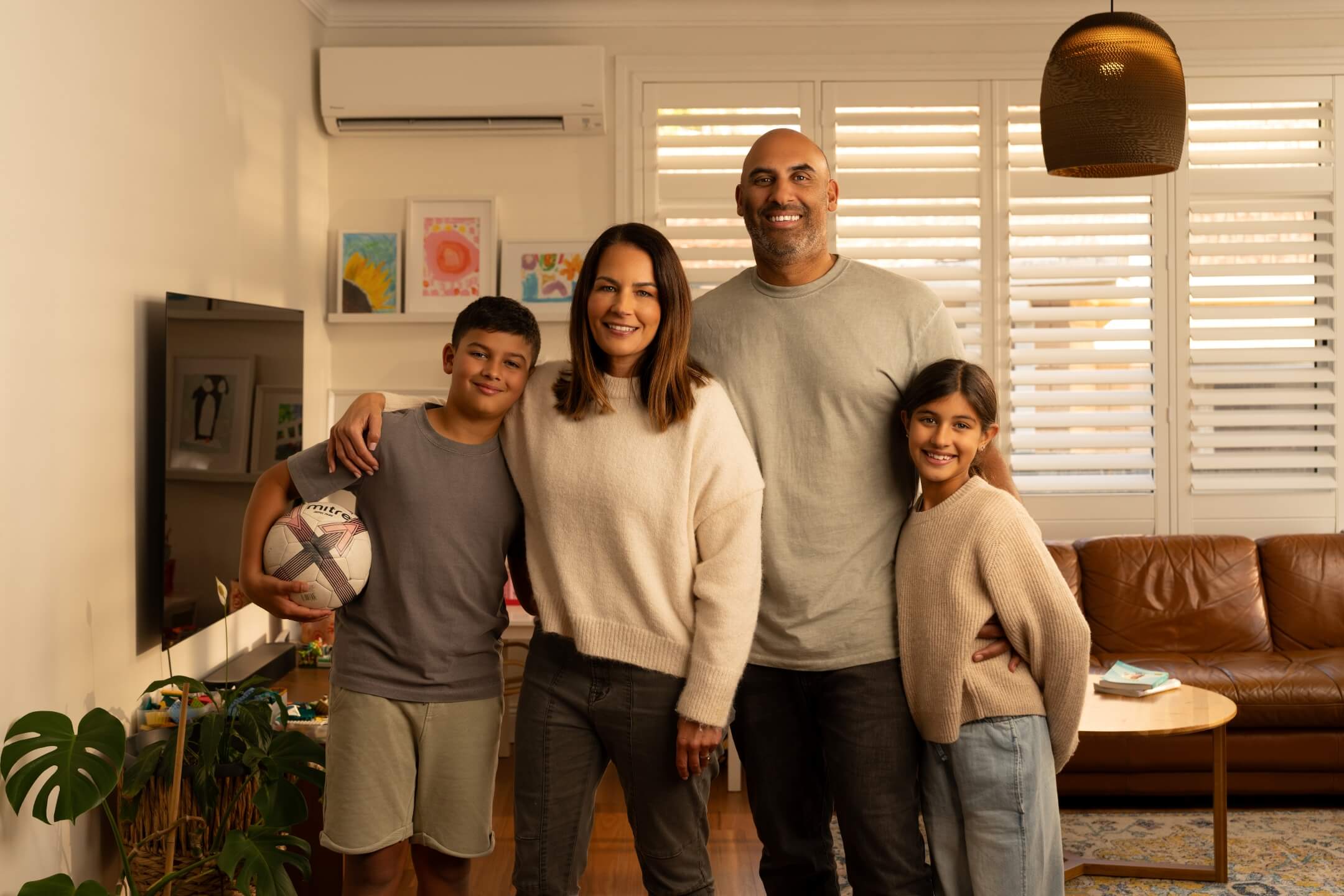 A family of a dad, mother, daughter and son, standing in their home living room